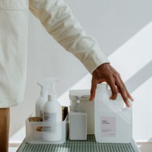Close-up of a man holding fabric softener surrounded by cleaning products in a minimalist setting.